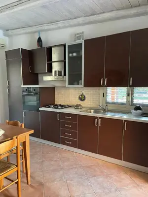 a kitchen with brown cabinets and a wooden table at Campofelice Casa vacanza in Palermo