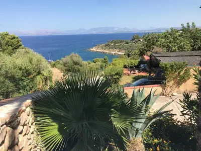 a view of the ocean from a house with a palm tree at Casa Bouganville in Scopello