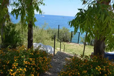 a white horse laying in the grass near the water at Casa Bouganville in Scopello