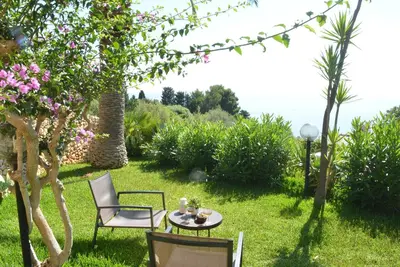 a patio with a table and chairs in the grass at Casa Bouganville in Scopello