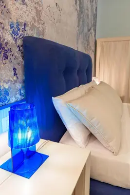 a bed with a blue headboard and a blue lamp on a table at CELSO 14 in Palermo