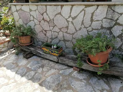 two potted plants sitting on a bench next to a stone wall at Villa Maricetta in Castellammare del Golfo