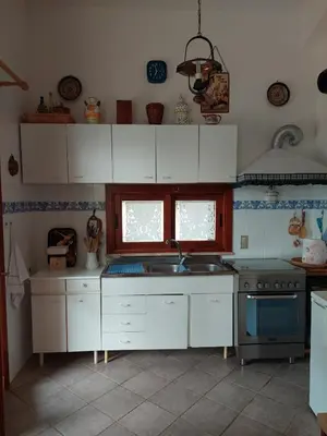 a kitchen with white cabinets and a sink and a stove at Villa Maricetta in Castellammare del Golfo