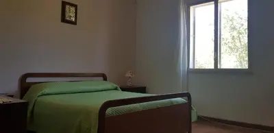 a bedroom with a bed with a green blanket and a window at Villa Andrea in Scopello
