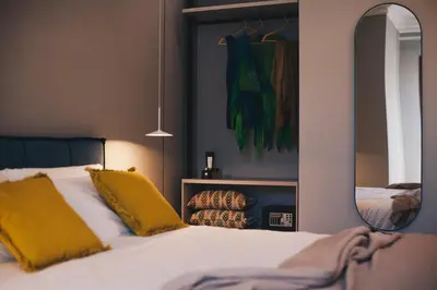 a bedroom with a bed with yellow pillows and a mirror at NITI Palace in Castellammare del Golfo