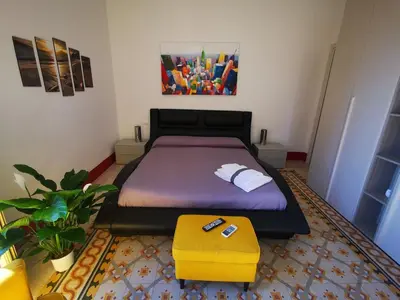 a bedroom with a bed and a yellow ottoman at La Dimora del Massimo in Palermo
