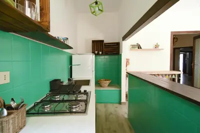a kitchen with green cabinets and a white refrigerator at Casa Azul in Terrasini