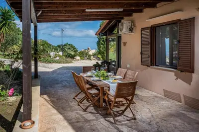 a table and chairs on the patio of a house at Villa Azuria con Piscina Privata Vista Mare in Scopello