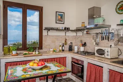 a kitchen with a table with a bowl of fruit on it at Villa Azuria con Piscina Privata Vista Mare in Scopello