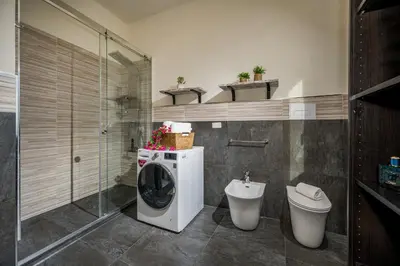 a bathroom with a washing machine and a toilet at Villa Azuria con Piscina Privata Vista Mare in Scopello