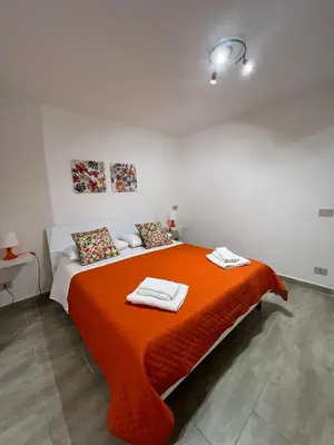 a bedroom with a large orange bed with towels on it at Trentuno Mondello Apartments in Mondello