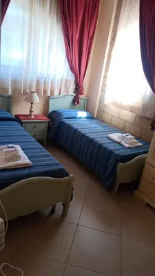 two beds in a room with two windows at La Casa di Martorana in Palermo