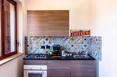 a kitchen with a sink and a coffee sign on the wall at Casa Vespucci in Isola delle Femmine