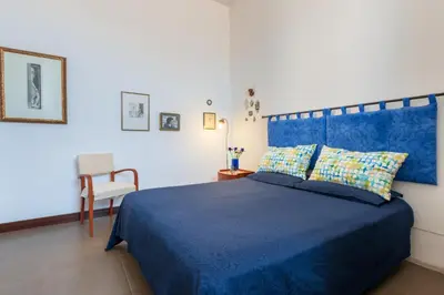 a bedroom with a blue bed and a chair at A Casa Dell' Artista in Palermo