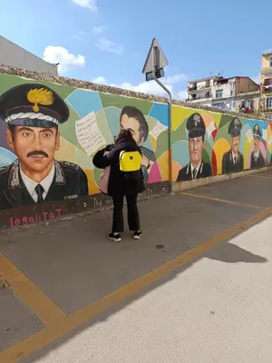 a woman taking a picture in front of a mural at Dimora al Capo in Palermo