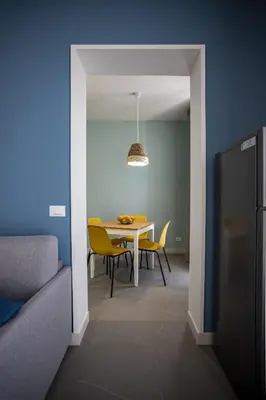 a dining room with a table and yellow chairs at Acquarò Suite Apartments in San Vito lo Capo