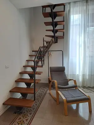 a living room with a spiral staircase and a chair at Palazzo Caltagirone Suite in Palermo