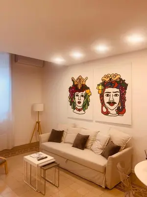 a living room with a couch and three paintings on the wall at Palazzo Caltagirone Suite in Palermo
