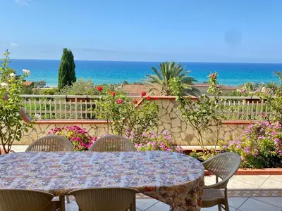 a table and chairs with the ocean in the background at Villa Mare Giuggiola in Alcamo Marina