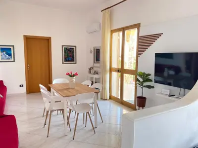 a dining room with a table and chairs and a tv at Villa Mare Giuggiola in Alcamo Marina