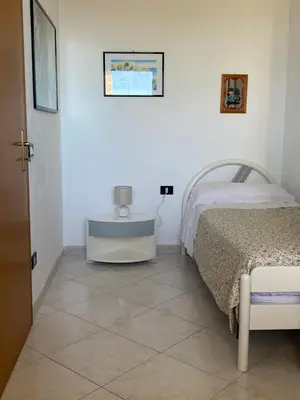a white bedroom with a bed and a table at Villa Mare Giuggiola in Alcamo Marina