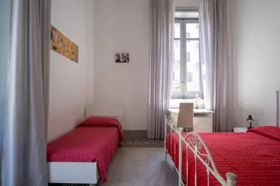 a bedroom with two beds with red sheets and a window at Rome 118 in Palermo
