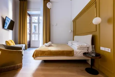 a bedroom with a bed and a chair and a table at Vespri Luxury Rooms & Suites in Palermo