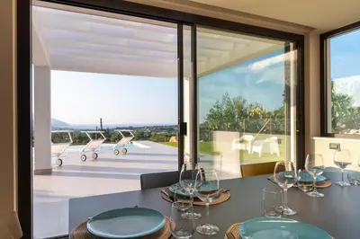 a dining room with a table with wine glasses at Villa vista mare con piscina a sfioro a Scopello in Castellammare del Golfo