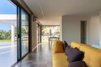 a living room with a yellow couch and a table at Villa vista mare con piscina a sfioro a Scopello in Castellammare del Golfo