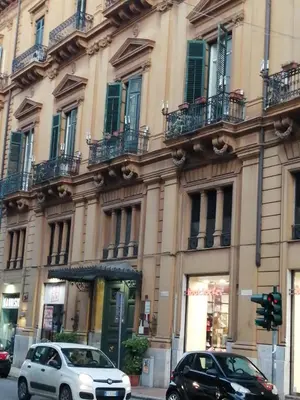 two cars parked in front of a large building at suite ruggero settimo in Palermo