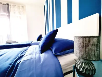 a bedroom with a bed with blue pillows and a lamp at Enne's Apartments in the heart of Palermo in Palermo