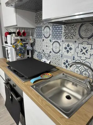 a kitchen with a sink and a laptop on a counter at Casetta Blu Mondello zona Partanna in Palermo