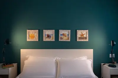 a bedroom with a blue wall with four pictures above a bed at Nerissa suites&rooms in Terrasini