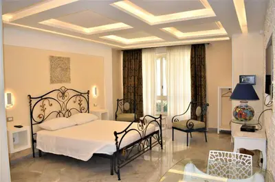 a bedroom with a bed and chairs in a room at Federico 70 Zaffiro Luxury in Palermo
