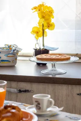 a table with a pie and a vase with yellow flowers at Butterfly House in Trappeto