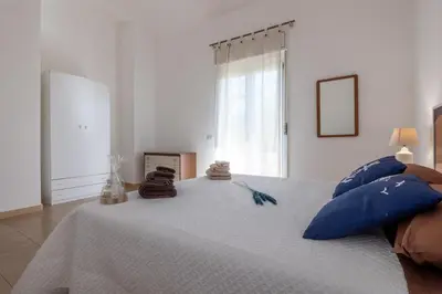 a bedroom with a white bed with blue pillows at Butterfly House in Trappeto