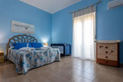 a bedroom with blue walls and a bed and a dresser at Butterfly House in Trappeto