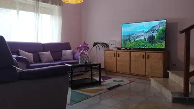 a living room with a purple couch and a flat screen tv at Butterfly House in Trappeto