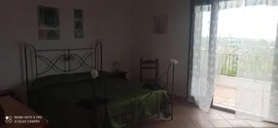 a bedroom with a bed and a large window at House Italia Holiday in Trabia