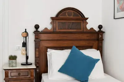 a bed with a wooden headboard and a blue pillow at iFlat Palazzo Ragusi in Palermo