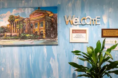 a painting on a blue wall with a plant at Federico 70 Smeraldo in Palermo