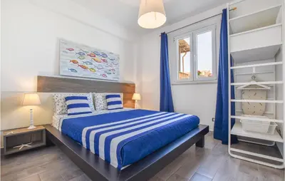 a bedroom with a bed with blue and white sheets at 2 Bedroom Amazing Apartment In Trappeto in Trappeto