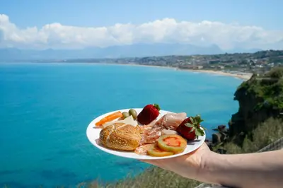 a person holding a plate of food in front of the ocean at SOL Y MAR Camere e Appartamenti in Castellammare del Golfo