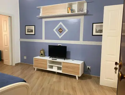 a bedroom with a tv on a blue wall at Luna Blu Apartment in Palermo