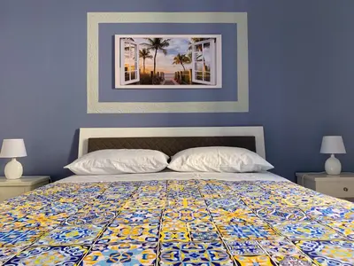 a blue bedroom with a bed with a colorful quilt at Luna Blu Apartment in Palermo