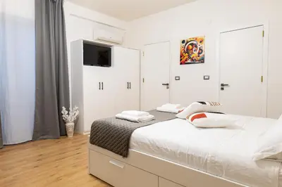 a white bedroom with a bed and a flat screen tv at Sweet Home in Palermo