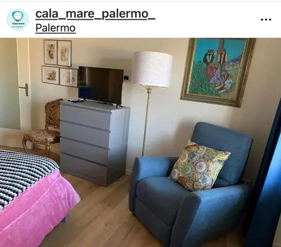 a bedroom with a bed and a blue chair and a television at CALA MARE in Palermo