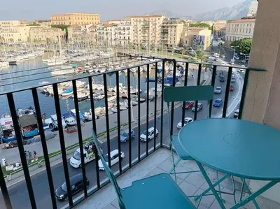 a balcony with a blue table and chairs and a harbor at CALA MARE in Palermo