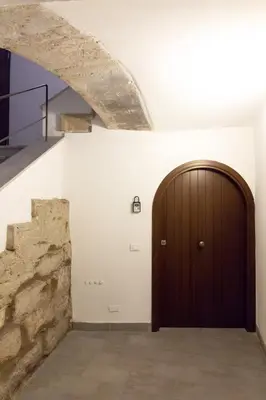 a hallway with a wooden door and a stone wall at Monolocale Sant'Andrea in Palermo