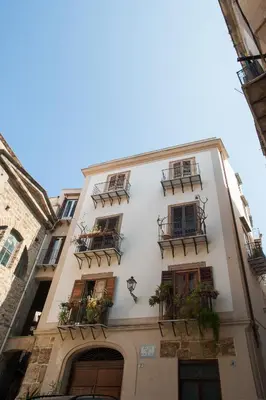 a white building with balconies and plants on it at Casa Miqvà - Rooms in shared apartment in Palermo